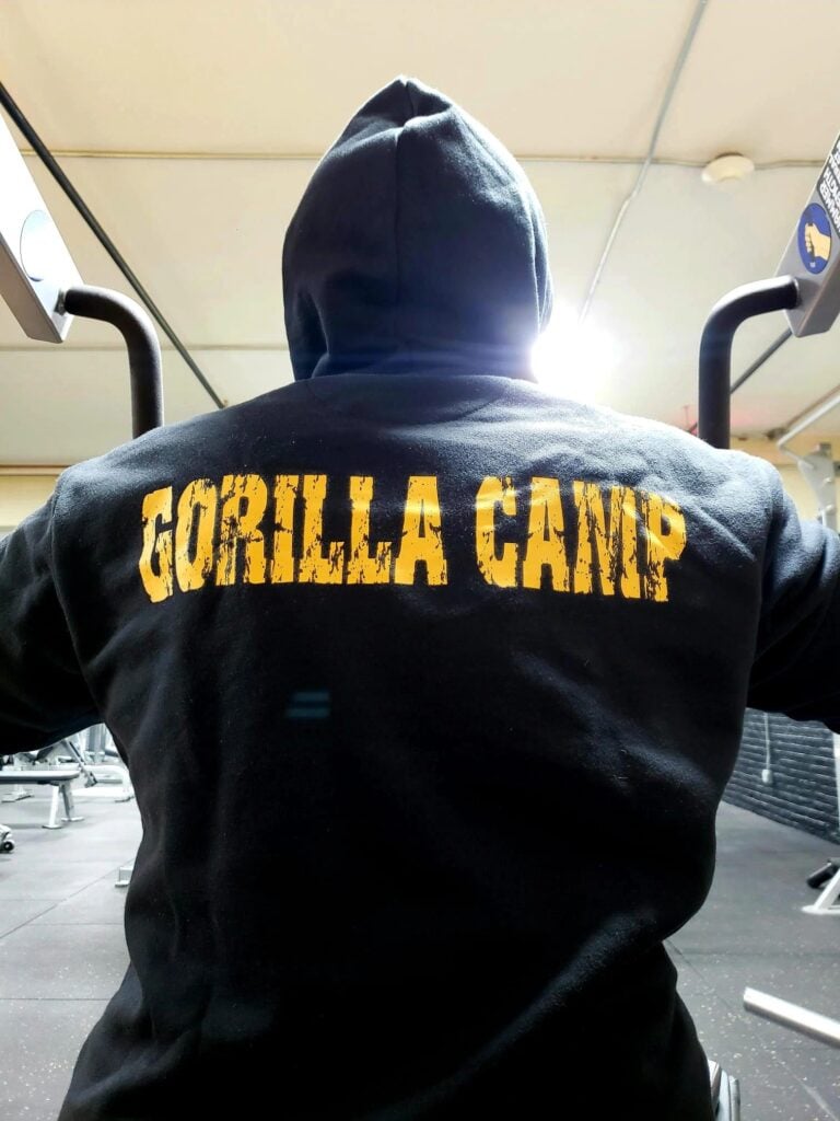 Member in a black Gorilla Camp hoodie training on a machine in the AUCC weight room